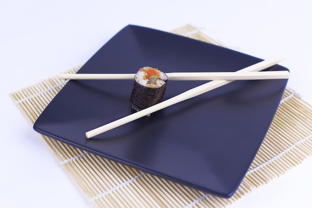 Primer plano de sushi y palillos en un plato negro