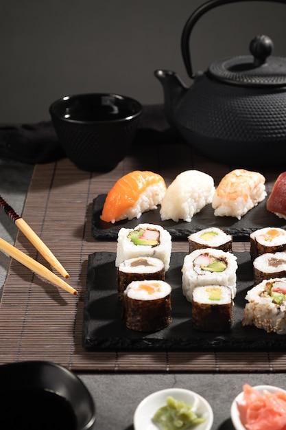 Primer plano de sushi de variedad fresca sobre fondo oscuro. Juego de sushi y té japonés. Formato vertical.