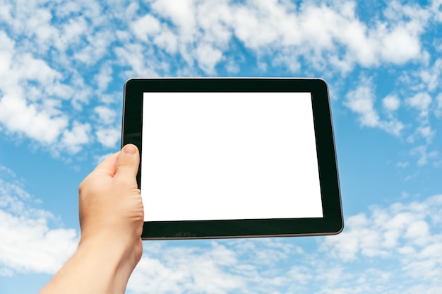 Primer plano de la tableta en la mano contra el fondo del cielo.