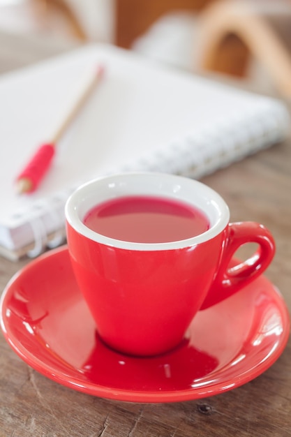 Primer plano de una taza de café contra un libro y un lápiz en la mesa