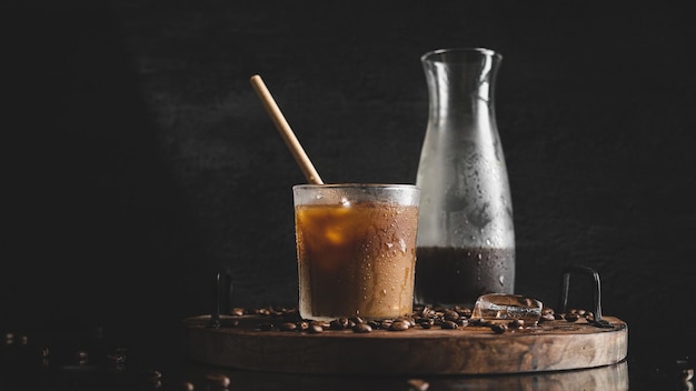 Primer plano de una taza de café con hielo y una botella en el barril