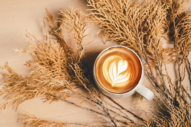 Primer plano de la taza de café con leche capuchino caliente con arte latte en forma de corazón y flores comida y