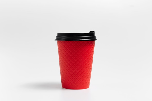 Primer plano de una taza de café para llevar de papel rojo sobre fondo blanco.