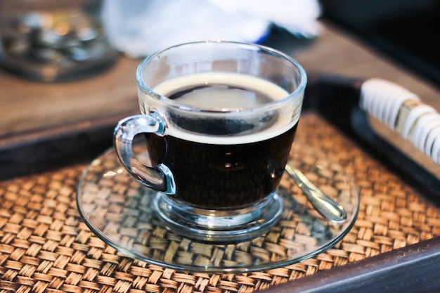 Un primer plano de una taza de café negro servido en una tazón de vidrio