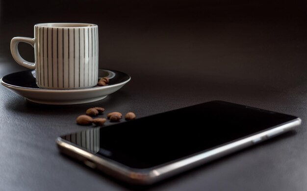 Foto primer plano de una taza de café por teléfono móvil en la mesa