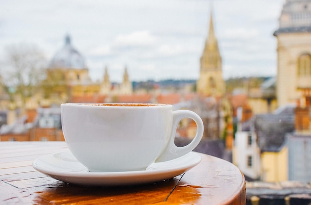Primer plano de la taza en la mesa contra los edificios de la ciudad