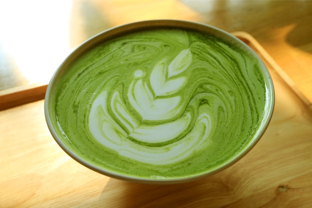 Primer plano de una taza de té verde Matcha Latte caliente en una bandeja de madera