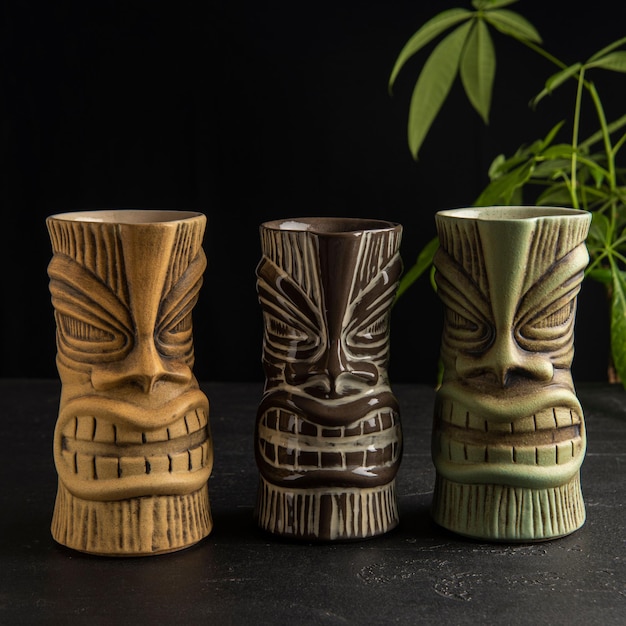 Un primer plano de tazas de tiki en la mesa contra un fondo oscuro