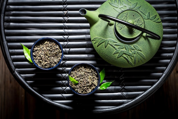 Primer plano de té con tetera en la mesa de bambú negro