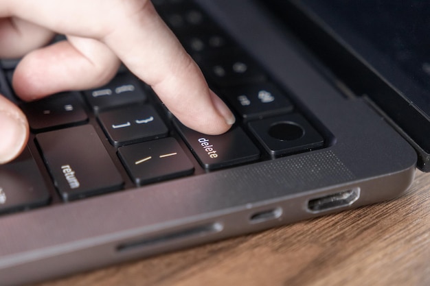 primer plano de la tecla de eliminación presionada con el dedo en el teclado de la computadora portátil con diseño moderno