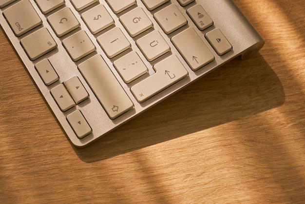 Foto primer plano del teclado bluetooth en una mesa de madera con luz natural.