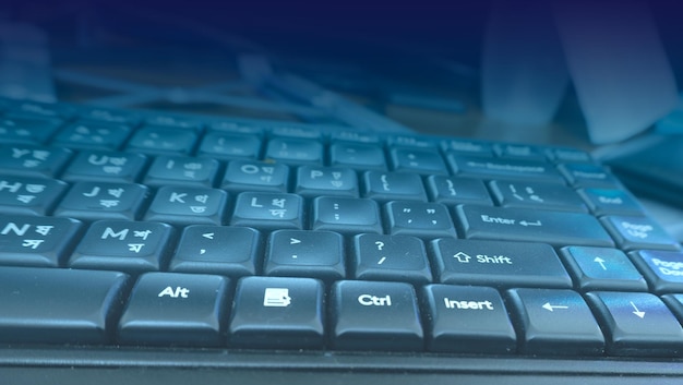 Primer plano de un teclado de computadora negro con un fondo de tecnología de superposición de luz azul