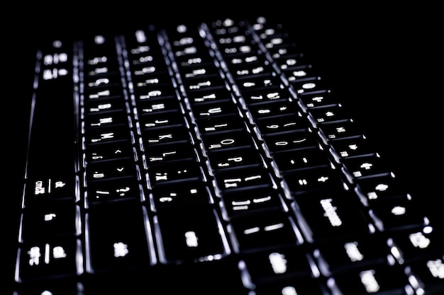 Primer plano del teclado con luz de fondo sobre un fondo negro Fragmento con teclas borrosas