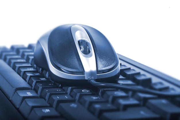 Primer plano del teclado y el ratón de la computadora contra un fondo blanco