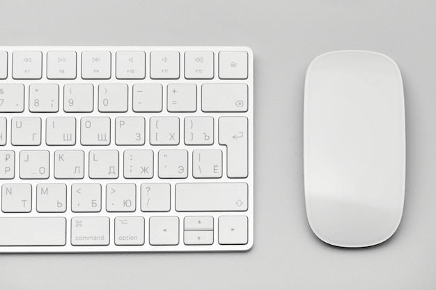 Primer plano del teclado y el ratón de la computadora sobre un fondo gris claro