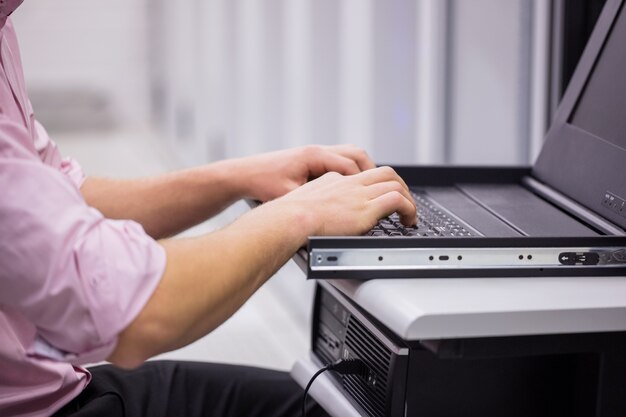 Primer plano de técnico sentado usando la computadora portátil para diagnosticar servidores