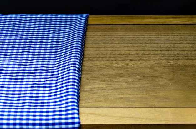 Primer plano de tela de algodón azul a cuadros sobre una mesa de madera.