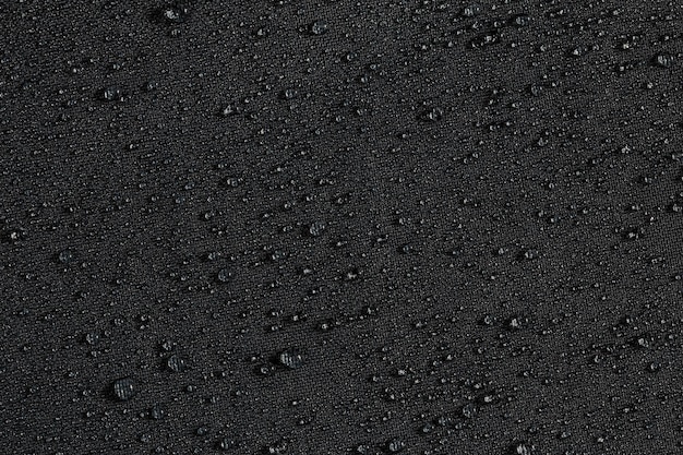 Primer plano de tela plana hidrofóbica impermeable gris oscuro con fondo de gotas de lluvia
