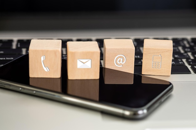 Primer plano de un teléfono inteligente con bloques de madera en una computadora portátil