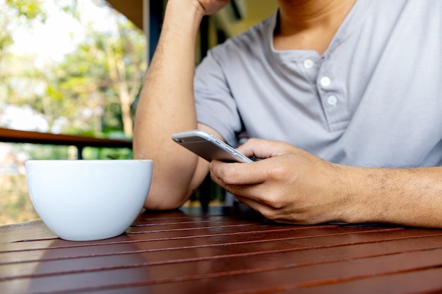 Primer plano de teléfono en manos de un hombre sentado en una cafetería.