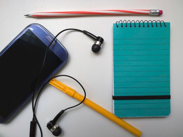 Primer plano de un teléfono móvil y bolígrafos sobre un fondo blanco