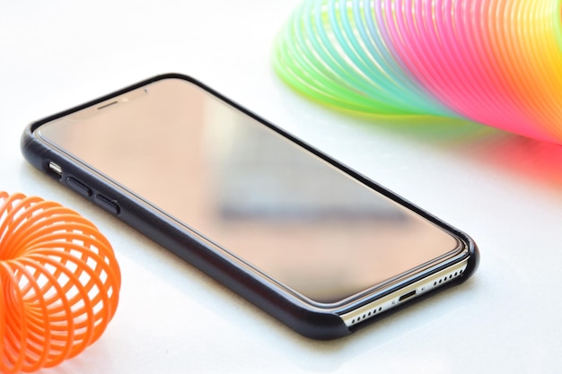 Primer plano de un teléfono móvil con juguetes coloridos en la mesa