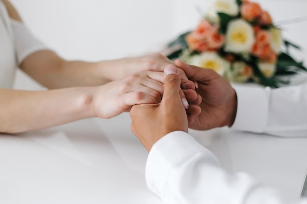 Primer plano del tema de la boda tomados de la mano recién casados toques suaves