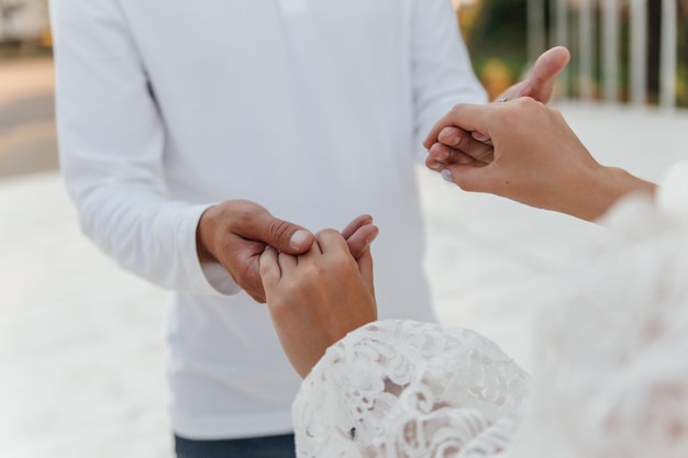 Primer plano del tema de la boda tomados de la mano recién casados toques suaves