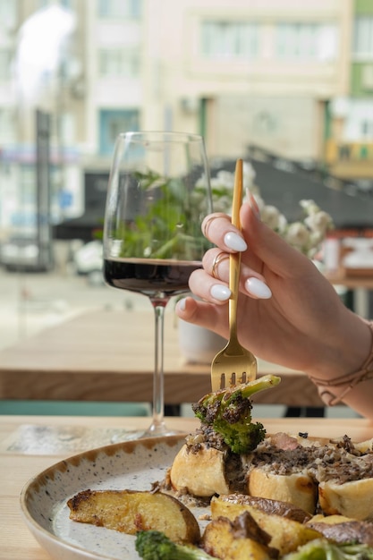 Un primer plano de un tenedor en la mano de una mujer sobre un plato con comida deliciosa en un restaurante