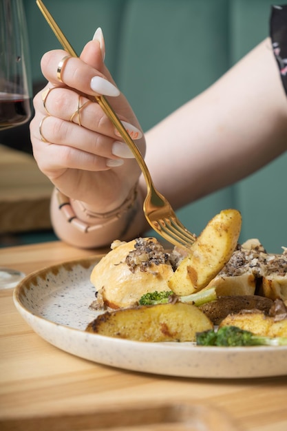 Un primer plano de un tenedor en la mano de una mujer sobre un plato con comida deliciosa en un restaurante