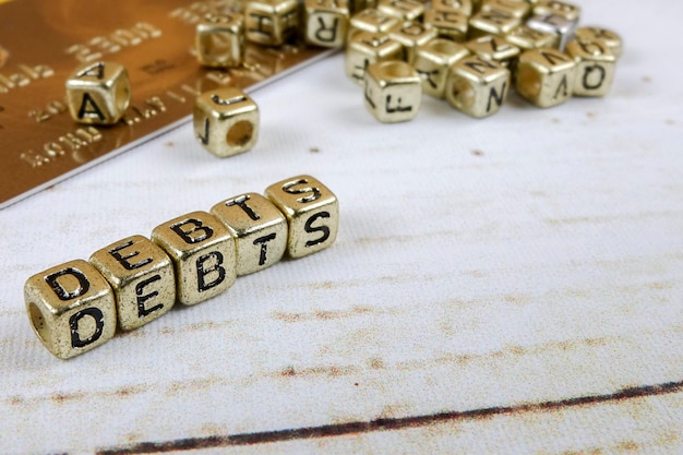 Primer plano del texto de la deuda hecho con bloques de juguete dorados en la mesa