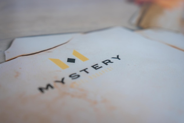 Primer plano del texto misterioso con el logotipo amarillo de M en superficie blanca