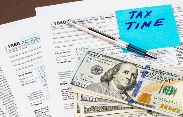 Primer plano del tiempo de impuestos - escrito en notas adhesivas con dinero.