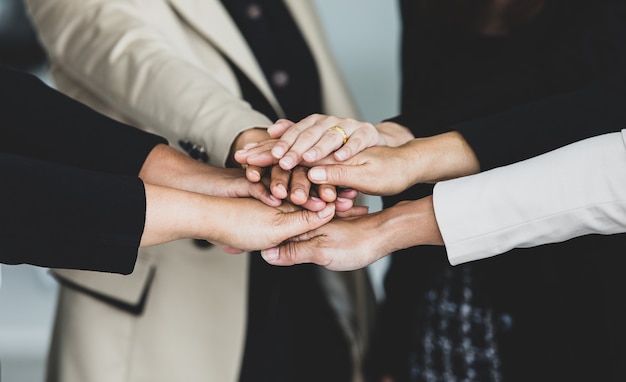 Foto primer plano de tomados de la mano del grupo de mujer de negocios exitosa irreconocible no identificado en traje formal lleva empoderar aliento como acuerdo de asociación de trabajo en equipo de confianza.