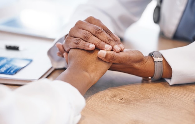 Primer plano tomados de la mano y médico con apoyo para el paciente con consulta de escucha y empatía en el escritorio Mujer médica y mano amiga para atención solidaria y asesoramiento para la salud con malas noticias