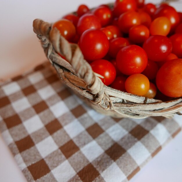 Primer plano de tomates cereza en una canasta de mimbre en la mesa