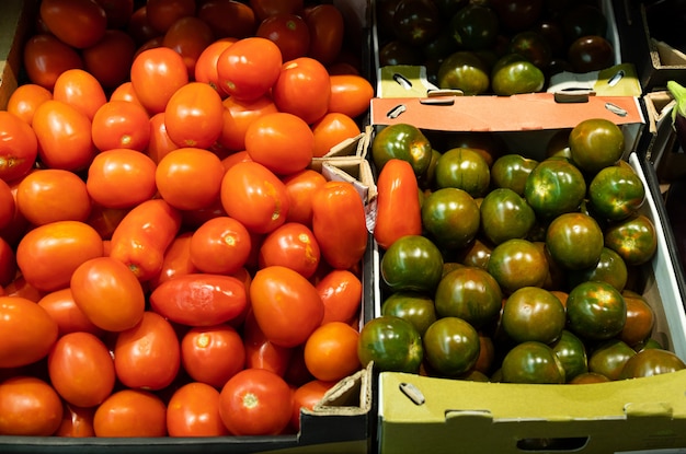 Primer plano de tomates rojos suaves y variedad verde de tomates en el mostrador de la tienda de comestibles