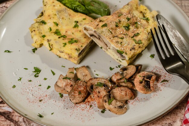 Primer plano de una tortilla de champiñones cortada por la mitad y servida en un plato con unos champiñones salteados