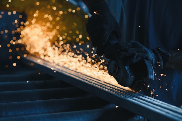 Foto primer plano de un trabajador cortando metal con molinillo chispas mientras se muele hierro baja profundidad de enfoque