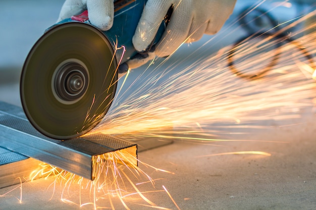 Primer plano de trabajador cortar metal con molinillo