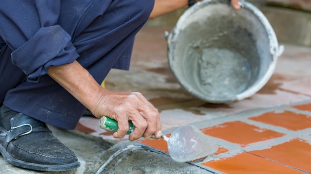 Foto primer plano de un trabajador manual reparando el piso de baldosas