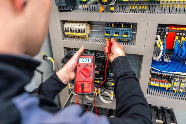 Foto primer plano de un trabajador reparando un panel del sistema eléctrico