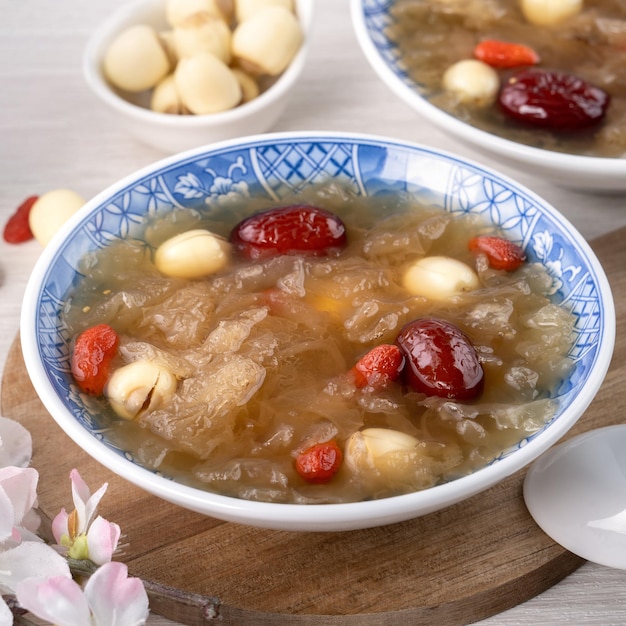 Primer plano de la tradicional sopa de hongos blancos de nieve dulce china con semillas de loto, dátiles rojos, jujube y bayas de goji sobre fondo blanco