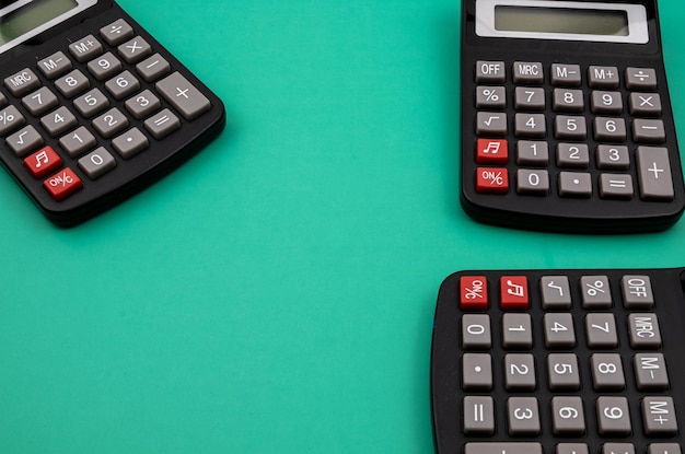 Primer plano de tres calculadoras en una mesa verde.