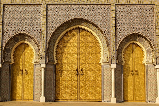 Primer plano de tres puertas ornamentadas de bronce y azulejos del Palacio Real en Fez, Marruecos
