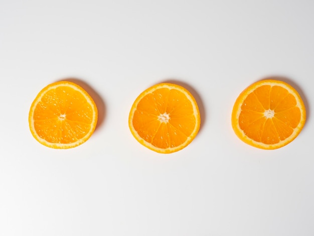 Primer plano de tres rodajas de naranja madura sobre un fondo blanco Deliciosa fruta hermosa llena de vitaminas Vista superior de la toma de estudio