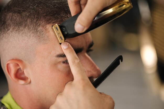 El primer plano del trímero de uso de peluquero para hacer una peluquería de corte de pelo moderna