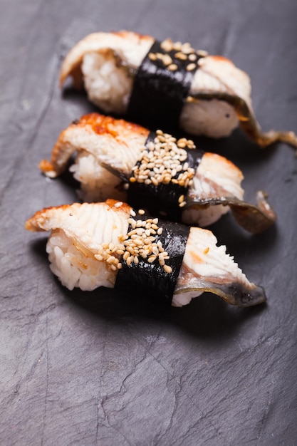 Primer plano de unagi nigiri sushi sobre un fondo de pizarra negra