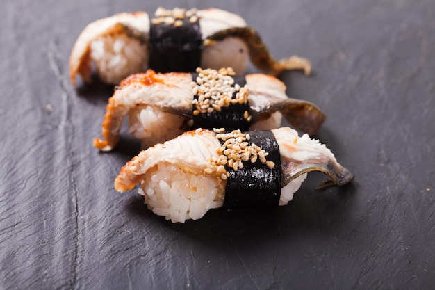 Primer plano de unagi nigiri sushi sobre un fondo de pizarra negra