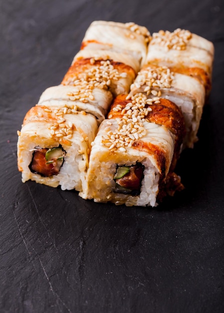 Primer plano de unagi sushi roll sobre un fondo de pizarra negra